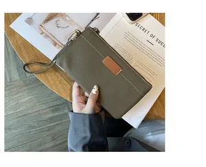 Detail view of an olive green pebble leather women's clutch with a wristlet strap.