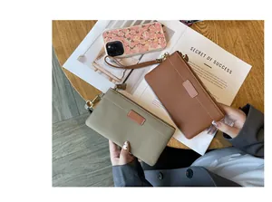 Genuine leather wristlet wallet with pebble grain texture shown in lifestyle setting