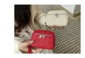 Close-up of red and beige mini leather coin purses with double zippers and wristlet straps