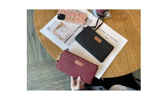 Detailed shot of a burgundy genuine leather clutch bag held over a stylish wooden table