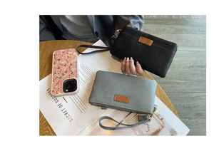 Lifestyle detailed view of genuine leather wristlet clutches in black and grey textures.