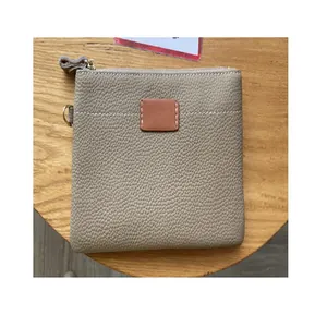 Top view of a taupe pebbled leather coin purse with zipper and tan patch.