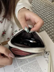 Compact double-zipper coin purse for women, showing interior capacity for cash and keys.