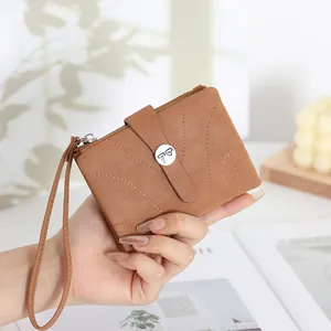 Gros plan d'un portefeuille en cuir marron avec papillon et dragonne en main.