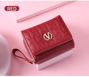 Detail of a red women's short wallet featuring wavy quilted stitching and gold V logo