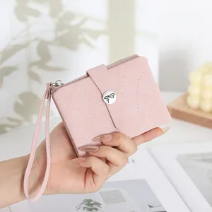 Gros plan d'un petit portefeuille rose en cuir PU avec fermoir nœud et dragonne pratique