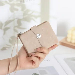 Détail d'un portefeuille beige pour femme avec bouton papillon et dragonne chic
