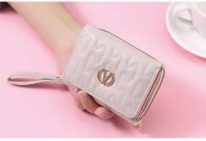 Macro view of a light pink quilted women's wallet featuring a gold V wheat ear emblem