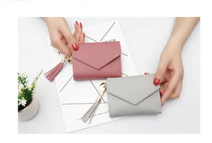 Macro view of pink and grey mini folding wallets with gold heart charms and tassels
