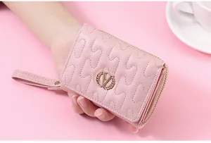 Close-up of pink quilted short wallet with gold V-shaped wheat emblem detail