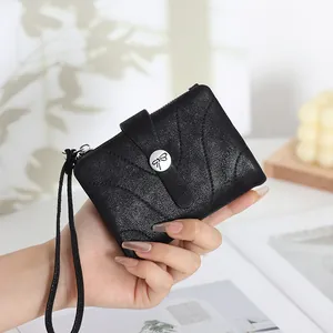 Détail d'un portefeuille noir en cuir avec une boucle papillon tenu par une main
