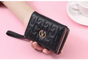 Close-up detail of a black quilted short wallet featuring a metal V logo and wrist strap