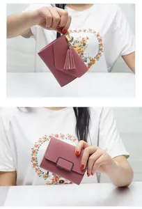 Close-up view of a stylish mauve women's mini tri-fold wallet featuring a heart tassel charm.