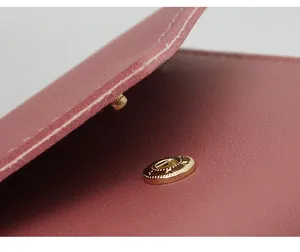 Macro view of golden snap button closure and stitching on pink leather wallet detail