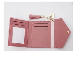 Detail view of pink tri-fold wallet showing interior card slots, ID window and heart tassel charm