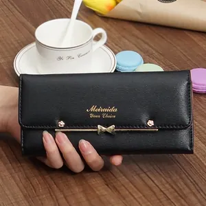 Detailed view of a black textured long wallet with a golden bow-knot and Meiruida logo