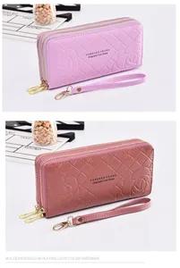 Detail view of double zipper long wallet with embossed rose pattern and wristlet