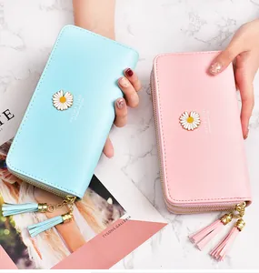 Detailed view of pink and light blue daisy wallets with double zippers and tassels.