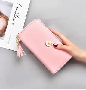 Close-up detail of a pink long wallet featuring a daisy ornament and a tassel puller