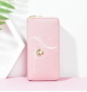 Nahaufnahme einer rosa langen Geldbörse für Damen mit elegantem Perlen- und Kleeblatt-Anhänger