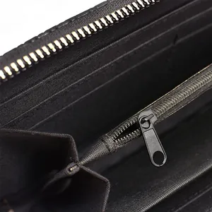 Detailed macro view showing the smooth metal zipper and compartments of a black woven wallet