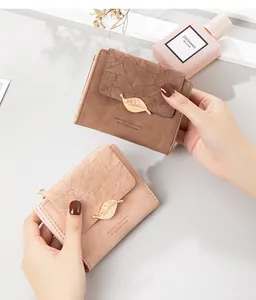 Detail view of minimalist matte leather short wallets with leaf pattern held by hands
