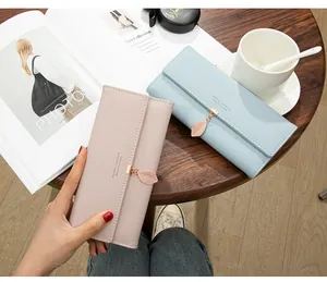 Close-up view of elegant tri-fold women's wallets featuring decorative leaf pendants