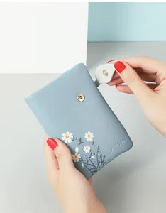 Close-up detail of a blue soft leather bifold wallet featuring a white daisy print design