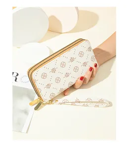 Detailed close-up of a stylish white floral double-zipper clutch wallet held by a hand for scale.