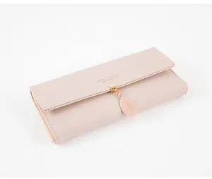 Detailed close-up view of a long pink leather tri-fold wallet featuring a delicate leaf pendant.