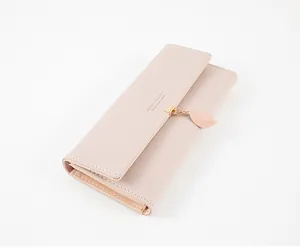 Close-up of an elegant light pink long wallet featuring a delicate leaf pendant and fine stitching.