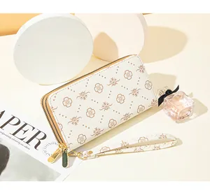 Close-up of elegant double-zipper long wallet with brown floral print and wristlet strap.