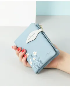 Close-up of a blue faux leather short wallet with daisy print and leaf buckle