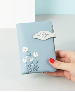 Close-up of a blue bi-fold leather wallet with daisy print and leaf closure