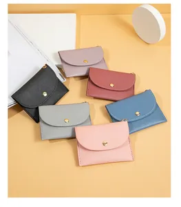 Vari portamonete mini in pelle colorata con chiusura a scatto su sfondo beige caldo