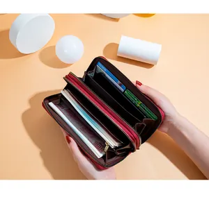 Gros plan d'un long portefeuille rouge à double fermeture éclair et grande capacité