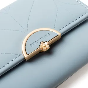 Detalle de cerca del cierre metálico dorado semicircular en una cartera de cuero azul