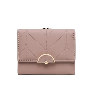 Detalle de una cartera triple de color rosa empolvado con un elegante broche dorado