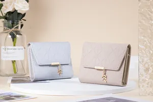 Close-up of quilted tri-fold wallets with gold leaf charms in light blue and beige