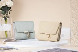 Lifestyle view of two short three-fold women's wallets with leaf pendants and plaid pattern.