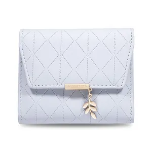 Detailed close-up view of light purple quilted tri-fold wallet with gold leaf pendant