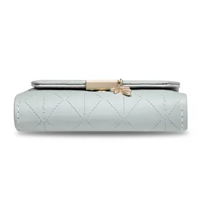 Close-up of the quilted mint green wallet's side view with a golden leaf charm