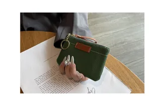 Gros plan d'un petit porte-monnaie élégant en cuir grainé vert foncé avec anneau doré