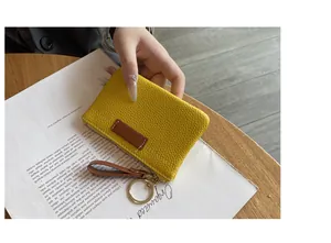 Gros plan d'un petit porte-monnaie en cuir jaune avec une dragonne marron élégante.