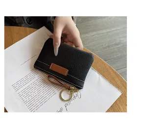 Vue détaillée du porte-monnaie en cuir noir grainé avec un anneau porte-clés doré
