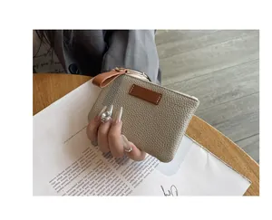 Vue détaillée d'un mini porte-monnaie en cuir beige texturé avec dragonne marron