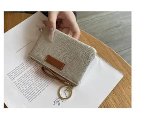 Gros plan d'un petit porte-monnaie en cuir beige avec anneau porte-clés intégré