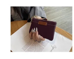 Détail d'un petit porte-monnaie en cuir violet grainé tenu par une main élégante