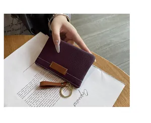 Gros plan d'un mini porte-monnaie en cuir grainé violet avec anneau porte-clés doré.