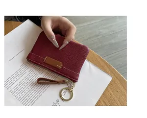 Gros plan d'un petit porte-monnaie en cuir bordeaux texturé avec un anneau porte-clés doré